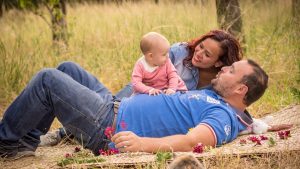 A family enjoys a relaxing picnic in a grassy field, focusing on bonding time with their baby.